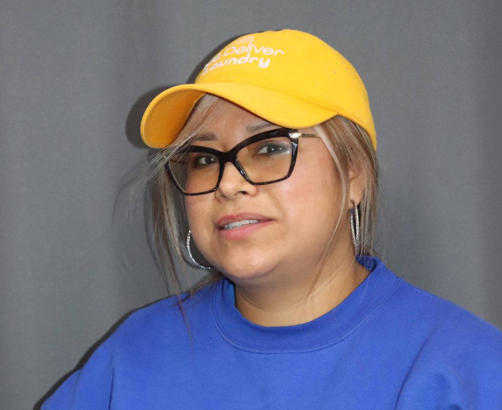 We Deliver Laundry team member wearing branded uniform inside a professional laundry facility.